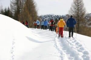 Familie mit Kindern wandert durch die verschneite Landschaft rund um den Petschnighof – Winterspaziergang in Kärnten mit Weitblick.