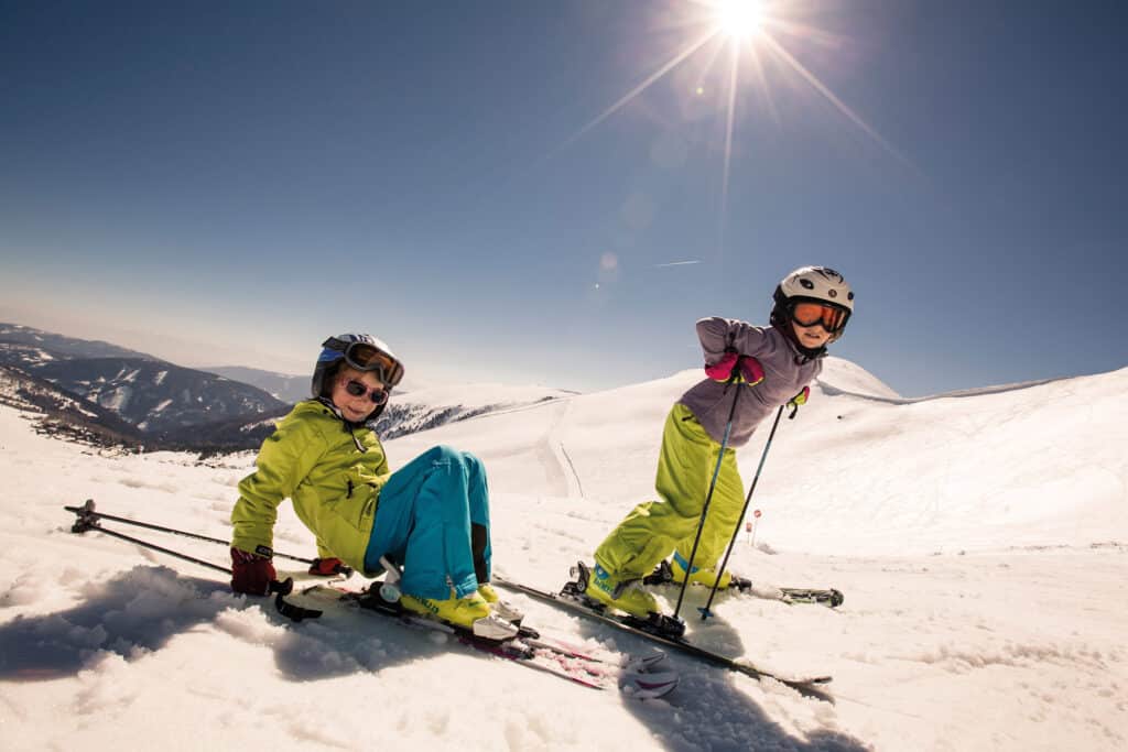 Familie mit Kindern beim Skifahren im Skigebiet am Falkert – sonniger Wintertag in Kärnten mit Panoramablick und kinderfreundlichen Pisten.